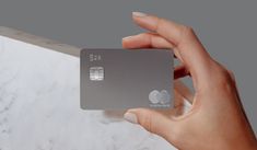 a person holding up a silver credit card