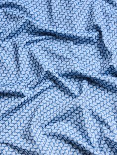 the blue and white fabric is very close to it's surface with small, wavy lines