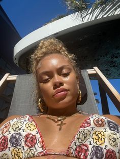 a woman with her eyes closed sitting in a chair next to a building and palm tree