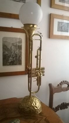 an old brass musical instrument on a table in a room with pictures and framed photos