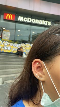 a woman wearing a pair of ear piercings in front of a mcdonald's