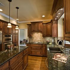 a large kitchen with granite counter tops and wooden cabinets, along with stainless steel appliances