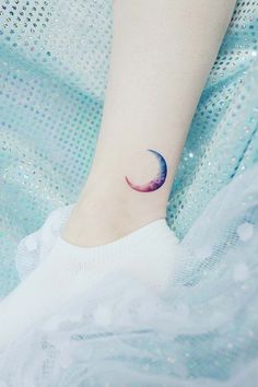 a woman's foot with a small crescent tattoo on her left ankle and the moon behind it