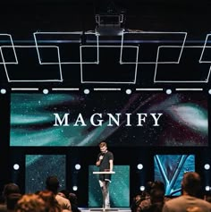 a man standing on top of a stage in front of a group of people at a convention