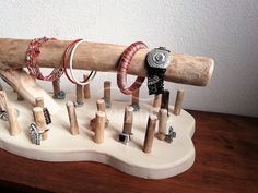 a collection of rings and bracelets are on a wooden stand next to a wall