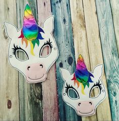 two unicorn masks are sitting on a wooden surface