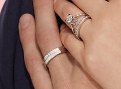 two people holding hands with wedding rings on their fingers and one wearing a diamond ring