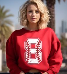 a blonde woman wearing a red sweatshirt with the number eight on it and baseball stitches