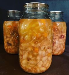 three jars filled with food sitting on top of a table