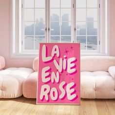 a pink sign that says la vie en rose on it in front of a white couch