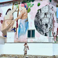 a woman is standing in front of a building with murals on the side and walls