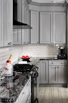 a kitchen with gray cabinets and marble counter tops