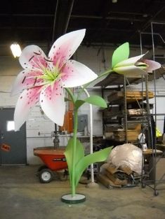 a large white and pink flower sitting on top of a green plant in a warehouse