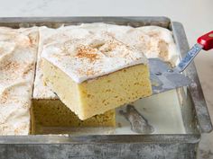 a piece of cake is being lifted from the pan by a spatula with powdered sugar on top