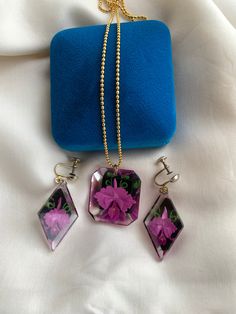 "We love these matching resin sets! Loving the shapes of this set - diamond earrings and square pendant. The flowers look to be orchids with little fancy green leaves.  The earrings have silver tone screw backs. The necklace chain does not look to be original as it is gold tone, while the rest of the hardware is silver. It comes in a Birks box but is not from Birks.  Condition: good condition with minimal wear-the large blue stone on the right earring is a bit loose, but still in its prongs. There is some visibility glue on the back side if the left earring which can not be seen when wearing.  Label: N/A Fabric Content: resin and metal base Size on Label: n/a Measurements: Earrings: Approx. 2\" in total length Necklace: pendant is approx 1.25\" and the chain is approx 11.5\" in length  *IM Vintage Cluster Ring, Fish Dress, Floral Resin, Length Necklace, Set Necklace, Square Pendant, Shell Jewelry, Floral Dress Summer, Faceted Glass