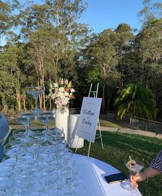 a table set up with wine glasses and menus for an outdoor wedding reception at the park