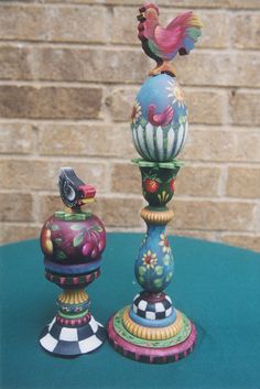 two colorful vases sitting on top of a blue table next to a brick wall