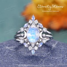 an opal and diamond ring on top of a blue rock with autumn leaves in the background