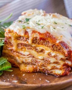 a wooden plate topped with lasagna covered in sauce and cheese next to a salad