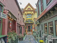 an alley way with many colorful buildings on both sides and flowers growing in the middle