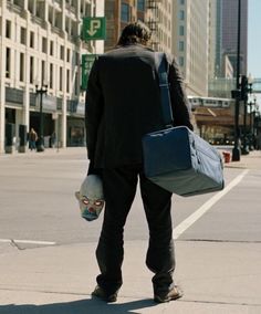 a man walking down the street with a bag on his back and a skull in his hand