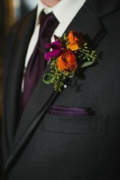 a man wearing a suit and tie with flowers on it's lapel flower