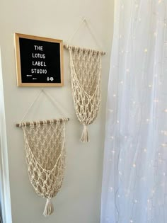 two macrame hangings on the wall with a chalkboard sign above them