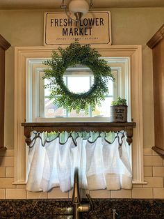 a kitchen sink under a window with a wreath above it