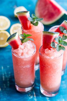 three glasses filled with watermelon and mint garnish next to lemon wedges