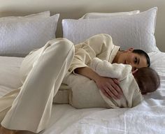 a woman laying on top of a bed with a baby wrapped up in a blanket