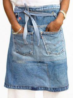 a woman is wearing an apron and has her hands in the pocket of her jean skirt