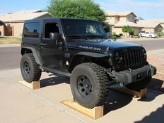 a black jeep parked on top of a wooden platform