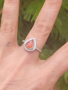 a woman's hand with a diamond ring on it and a pink stone in the middle