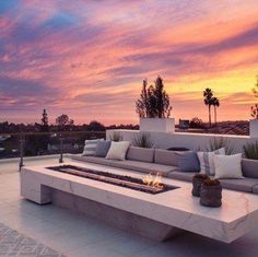 an image of a couch and fire pit on the patio with palm trees in the background