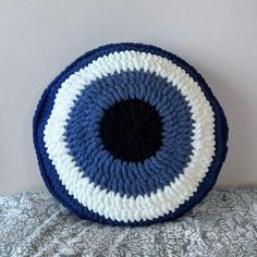 a blue and white crocheted basket sitting on top of a bed