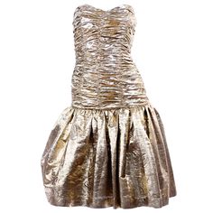 This is a fun vintage textured gold lurex strapless cocktail or party dress from the 1980's. The drop waist bodice is fully ruched and the skirt is lined with a tulle underskirt for fullness. The dress is fully lined in satin and closes with a back zipper. We estimate the dress to fit a modern day US size 4 but please use the measurement as a guide for the best fit. BUST: 34" WAIST: 24: HIPS: 36" LENGTH from underarm: 34" Pleated Strapless Dress For Party, Ruched Strapless Dress For Evening Party Season, Glamorous Gold Strapless Evening Dress, Ruched Strapless Dress For Party Season, Glamorous Gold Dress With Ruched Bodice, Gold Strapless Dress For Prom Season, Pleated Strapless Dress With Fitted Bodice For Party, Gold Strapless Dress For Summer Evenings, Gold Strapless Dress For Prom Evening