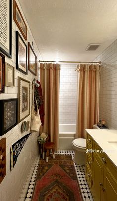 a bath room with a toilet a sink and pictures on the wall