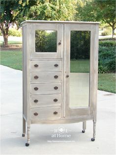 an old white cabinet with mirrored doors on the front and bottom drawers is sitting outside