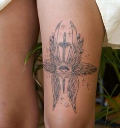 a woman's thigh with an angel tattoo on her leg and cross in the middle