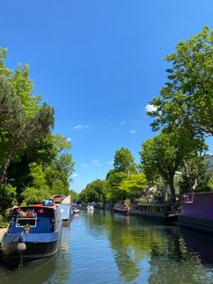 boats are lined up along the side of a narrow canal with trees lining both sides