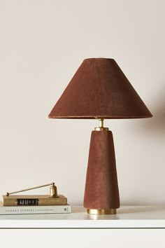 a lamp sitting on top of a table next to a book and a lamp shade