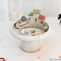 there is a miniature house on top of a small bowl that has been placed on the table