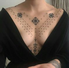 a woman with tattoos on her chest is holding a cell phone in her right hand