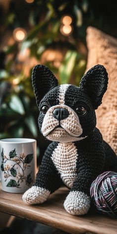 a small black and white dog sitting next to a coffee cup on a wooden table