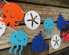 some paper cutouts are hanging from a string on a wooden wall with an octopus and crab theme