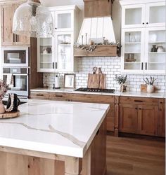 a kitchen with wooden cabinets and white marble counter tops, along with an island in the middle