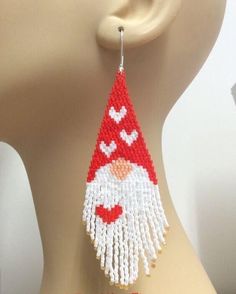 a close up of a person's head wearing a red and white beaded gnome earring