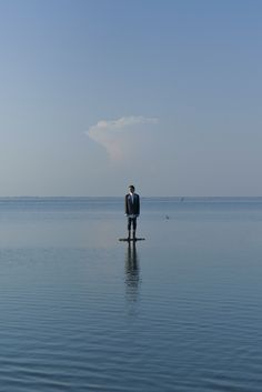 a man standing on top of a paddle board in the middle of a body of water