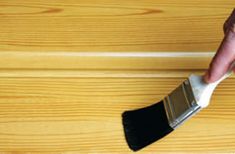 a person holding a paint brush on top of a wooden floor