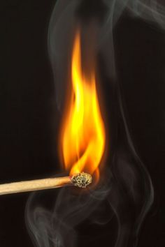 a burning matchstick with yellow and red flames on it's end against a black background